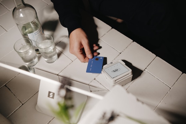 A customer holding a blue credit card while preparing to make a contactless payment using a SumUp point of sale system at a small business. The modern, minimalist setup highlights the ease and efficiency of digital transactions.